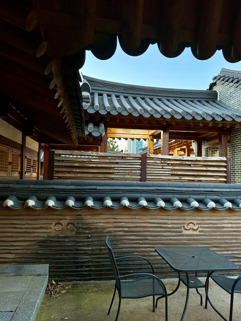 Courtyard view of Gyeongwonjae by Walkerhill, showcasing traditional Korean architecture with a tiled roof and a small outdoor seating area.