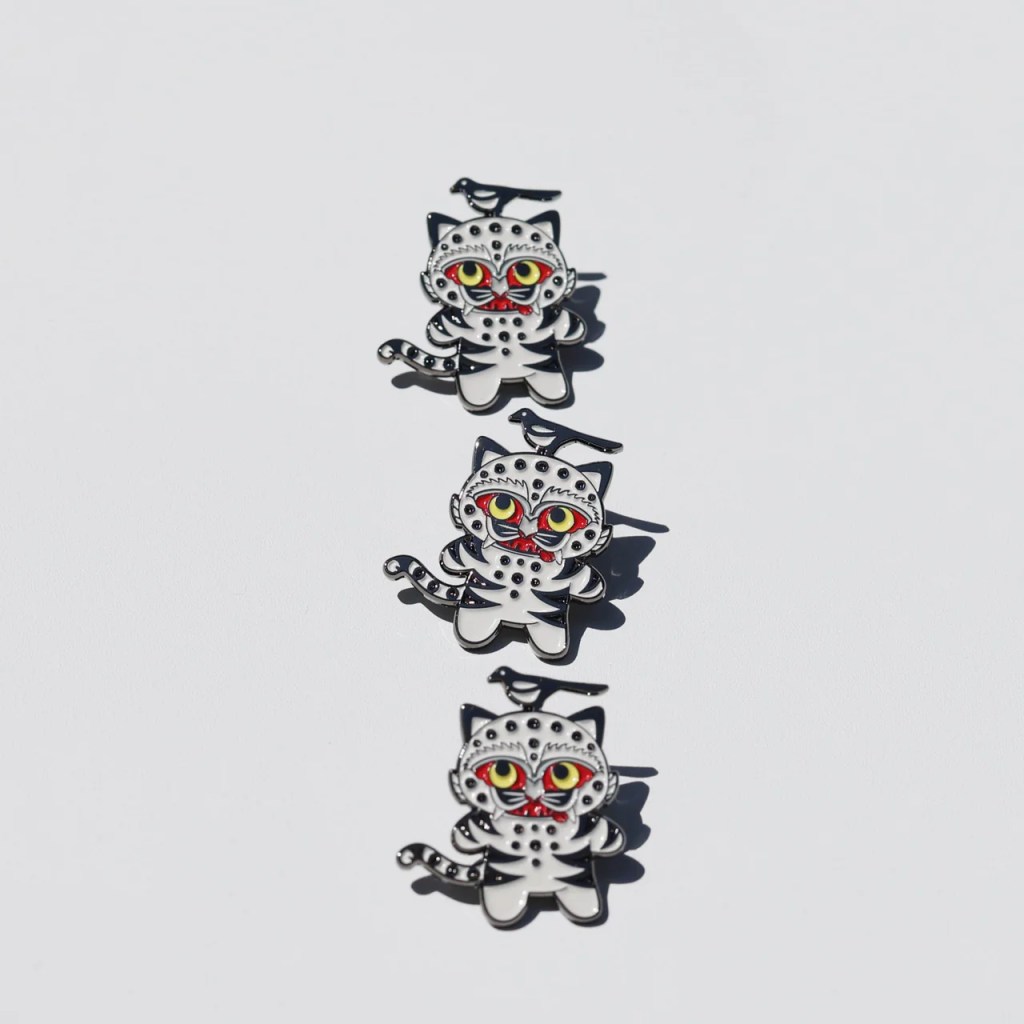 Three decorative badges featuring a whimsical design of a tiger and a magpie with exaggerated colorful features, set against a white background.